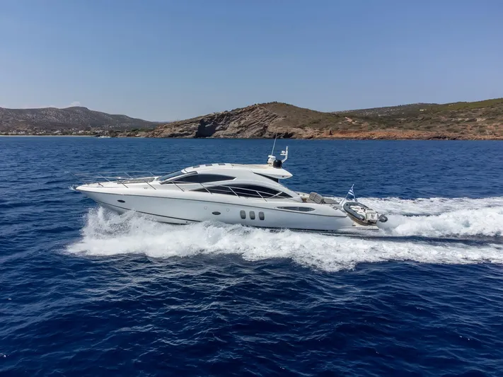 M/y Seaduced Yacht Photos Pics 2009 Sunseeker Predator 52 yacht cruising on blue ocean near rocky coastline.