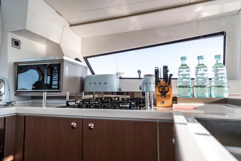 Signature Bali 5.4. (5+2 Cabins) Yacht Photos Pics Modern yacht kitchen with appliances, knife set, and water bottles, featuring sleek design. Bali 5.4, 2021.