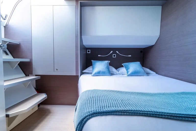 Signature Bali 5.4. (5+2 Cabins) Yacht Photos Pics Modern yacht cabin interior with cozy bed, blue pillows, and blanket, Bali 5.4, 2021 model.