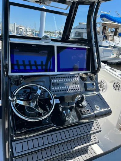 Sunset Chaser Yacht Photos Pics Control panel of 2023 Tidewater 320 CC Adventure boat with dual screens and steering wheel.