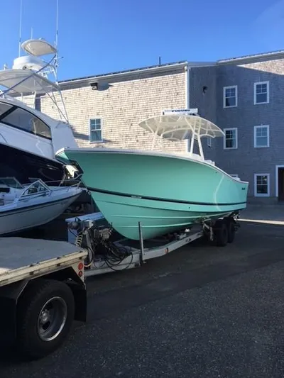 One Knot Yacht Photos Pics 2018 Regulator 31 boat on trailer, light blue hull, parked near a building.