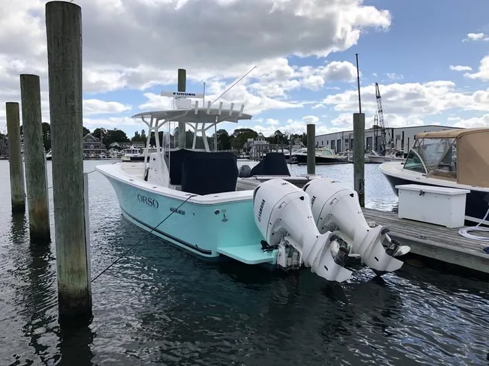One Knot Yacht Photos Pics 2018 Regulator 31 boat docked with twin outboard engines under a cloudy sky.