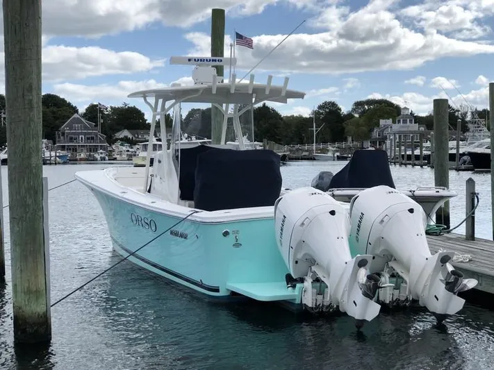 One Knot Yacht Photos Pics 2018 Regulator 31 boat docked with twin Yamaha engines, under a cloudy sky.