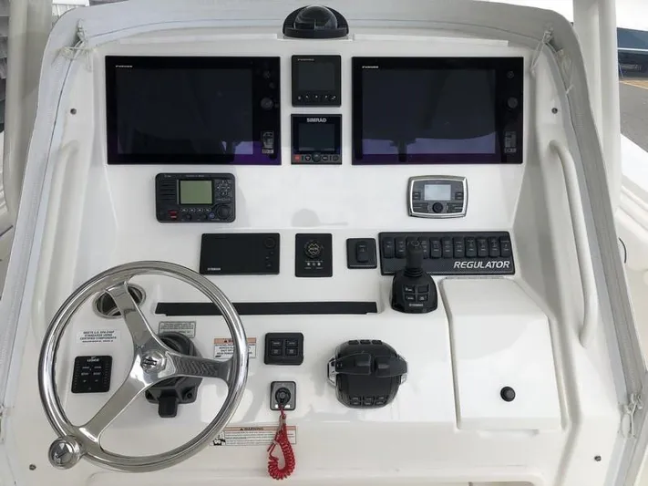One Knot Yacht Photos Pics Control panel of a 2018 Regulator 31 boat with steering wheel and electronic displays.