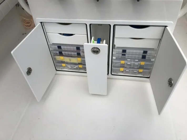 One Knot Yacht Photos Pics 2018 Regulator 31 boat storage compartment with organized tackle boxes and open doors.