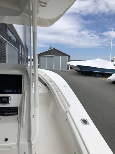 One Knot Yacht Photos Pics 2018 Regulator 31 boat docked near storage sheds under a partly cloudy sky.