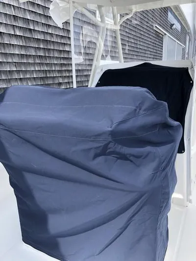 One Knot Yacht Photos Pics 2018 Regulator 31 boat with protective covers, docked near a shingled building.