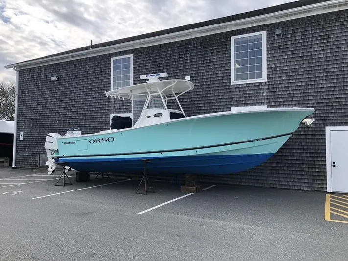 One Knot Yacht Photos Pics 2018 Regulator 31 boat on stands, parked beside a wooden building.
