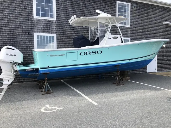 One Knot Yacht Photos Pics 2018 Regulator 31 boat with Yamaha engine, parked on stands near a building.