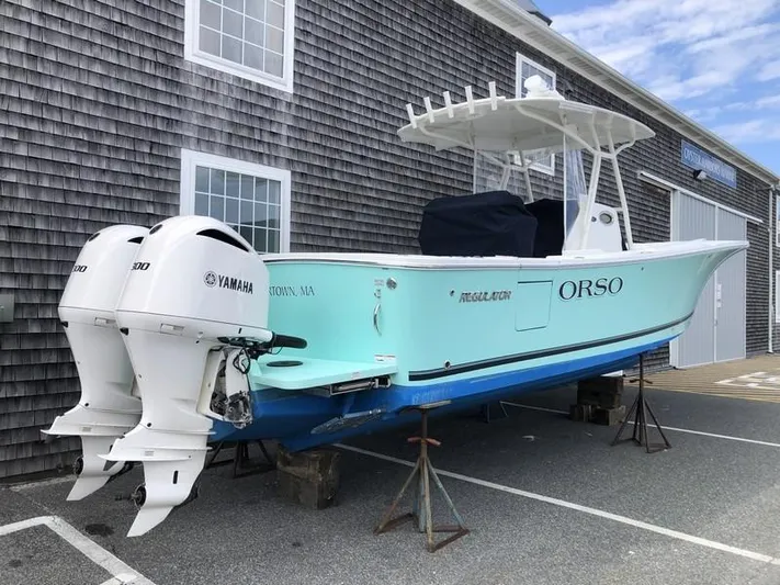 One Knot Yacht Photos Pics 2018 Regulator 31 boat with twin Yamaha engines, docked near a wooden building.