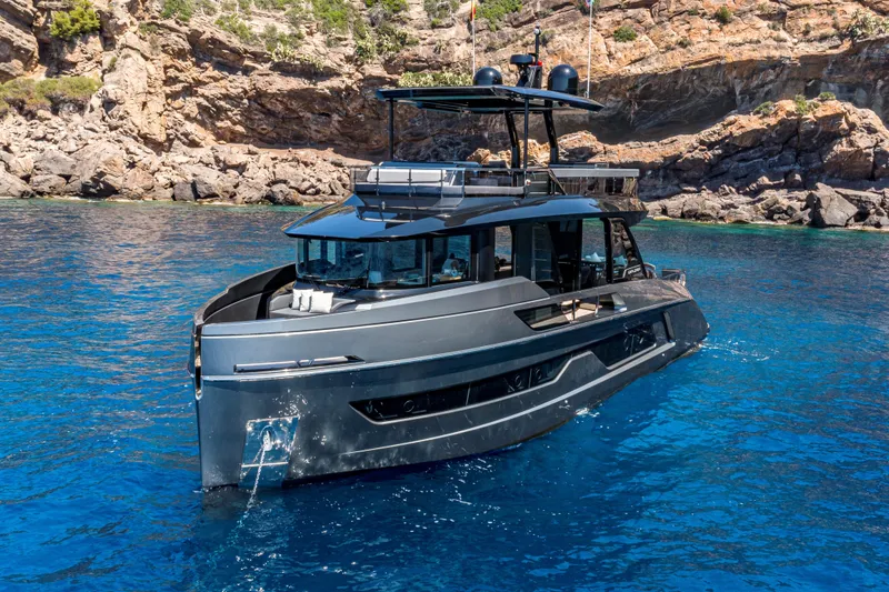  Yacht Photos Pics 2024 Explorer EX62 yacht in clear blue water near rocky coastline.