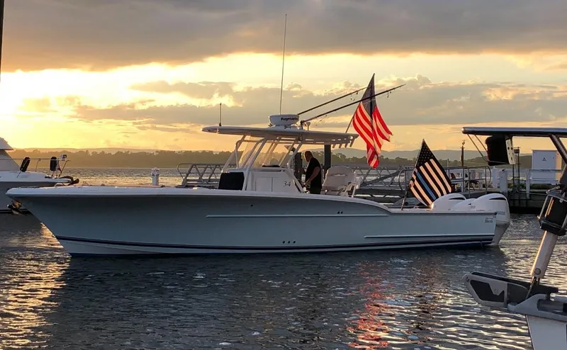  Yacht Photos Pics 2017 Buddy Davis 34 Center Console boat at sunset with flags, docked in calm waters.