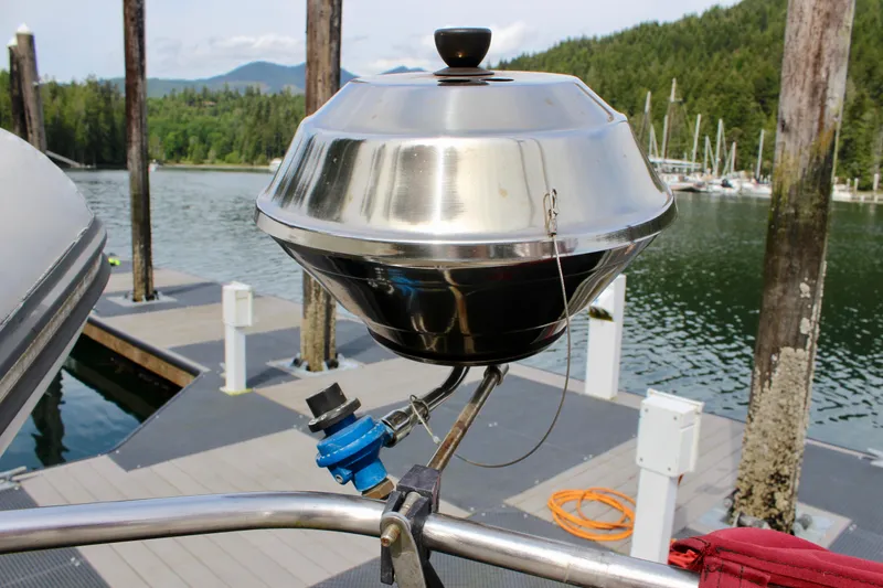 Phoenix Rising Yacht Photos Pics Stainless steel grill on a boat dock, surrounded by scenic lake and forest views.