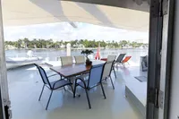 Outdoor dining area on 2004 Custom Bon Pelley catamaran with waterfront view.