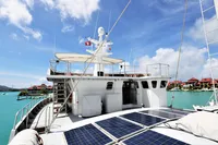 Custom 2004 Bon Pelley catamaran with solar panels, docked in a scenic marina.