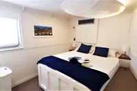 Cozy bedroom on 2004 Custom Bon Pelley catamaran with white decor and blue accents.