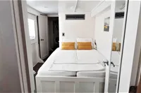 Cozy bedroom interior on 2004 Custom Bon Pelley catamaran with white bedding and yellow pillows.