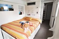 Cozy bedroom in 2004 Custom Bon Pelley catamaran with striped bedding and nautical decor.