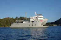 Custom Bon Pelley catamaran, 2004 model, anchored on calm waters with scenic background.