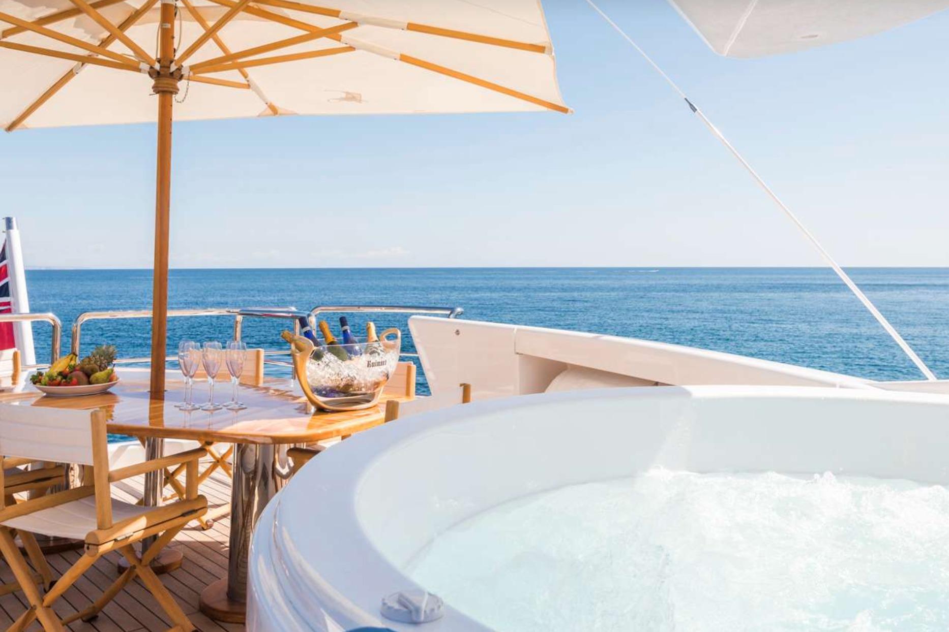 Luxury yacht deck with hot tub, dining table, and ocean view, Evolution 110, 2005 model.