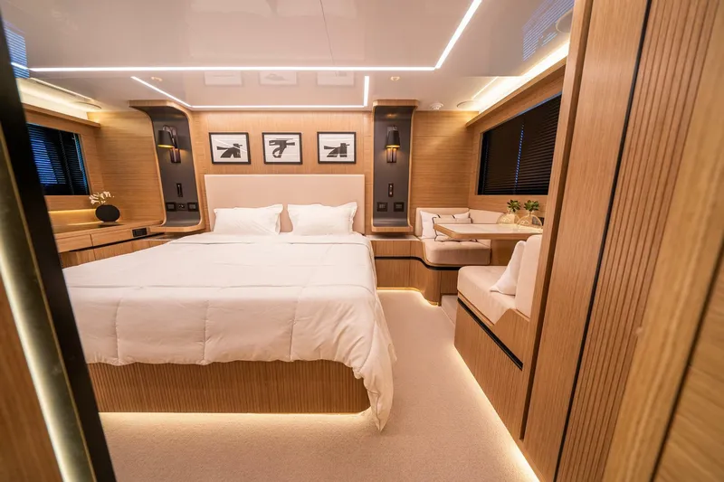  Yacht Photos Pics Luxurious bedroom interior of 2023 Pearl 62 yacht with modern wood finishes and ambient lighting.