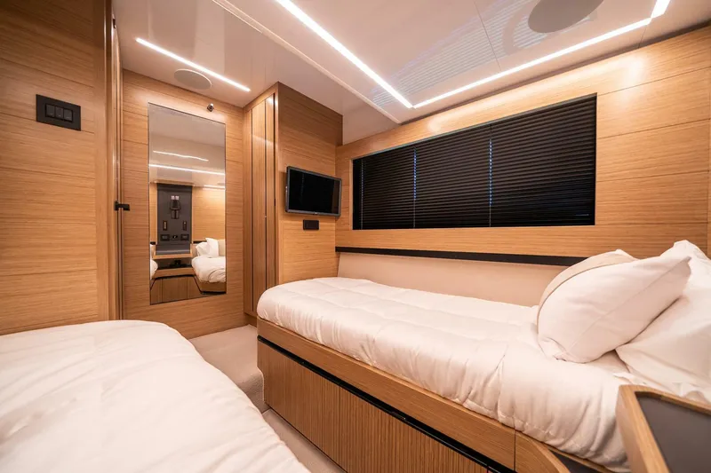  Yacht Photos Pics Luxurious cabin interior of 2023 Pearl 62 yacht with modern wood finish and twin beds.