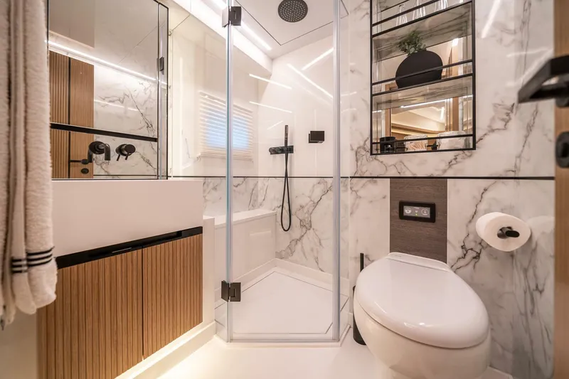  Yacht Photos Pics Modern bathroom with marble walls, glass shower, and sleek fixtures in a 2023 Pearl 62 model.