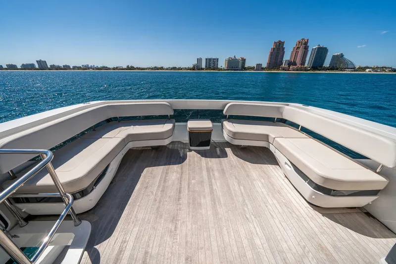  Yacht Photos Pics Luxurious Pearl 62 yacht deck with seating, overlooking a serene waterfront cityscape, 2023 model.