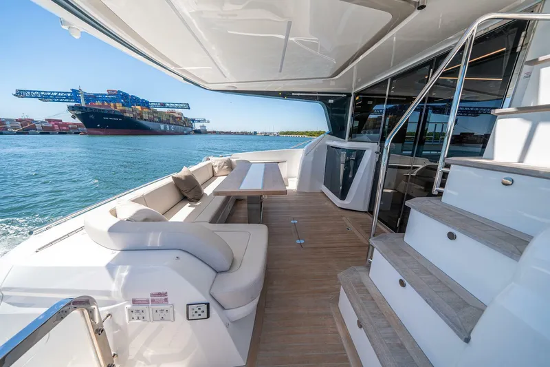  Yacht Photos Pics Luxurious 2023 Pearl 62 yacht deck with seating, overlooking a harbor.