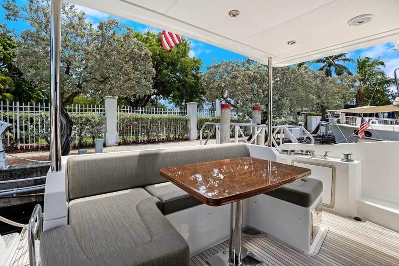  Yacht Photos Pics Azimut 50 Fly 2019 yacht deck with seating and table, docked near lush greenery.