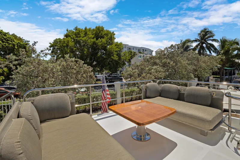  Yacht Photos Pics Outdoor seating area on 2019 Azimut 50 Fly yacht, featuring cushioned sofas and a wooden table.