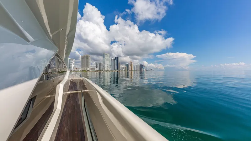 Golden 3 Yacht Photos Pics Luxury yacht Dominator 800 cruising near city skyline, clear blue skies, and calm waters.
