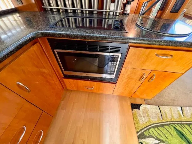 "kimberly Cay" Yacht Photos Pics 2003 Carver 360 Sport Sedan kitchen with microwave, wooden cabinets, and black countertop.