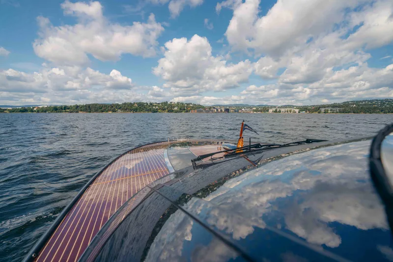  Yacht Photos Pics 2022 Riva Dolceriva yacht cruising on a scenic lake under a partly cloudy sky.