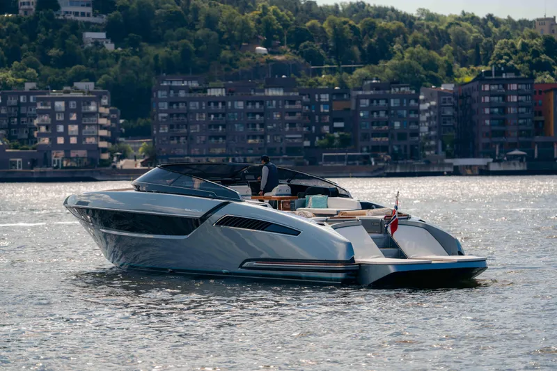  Yacht Photos Pics 2022 Riva Dolceriva luxury yacht cruising on a scenic waterfront with urban backdrop.