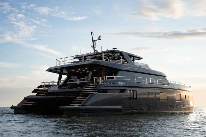 Petite Belle Yacht Photos Pics Luxurious 2025 Sunreef 100 Power yacht cruising at sunset on calm waters.