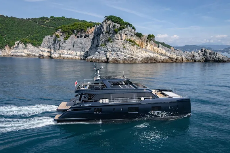 Petite Belle Yacht Photos Pics Luxurious 2025 Sunreef 100 Power yacht cruising near rocky coastline.