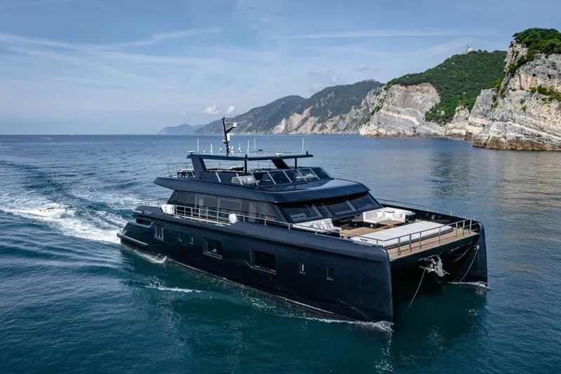 Petite Belle Yacht Photos Pics Luxurious 2025 Sunreef 100 Power yacht cruising near scenic coastal cliffs.