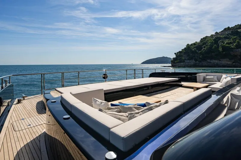 Petite Belle Yacht Photos Pics Luxurious Sunreef 100 Power yacht deck with elegant seating, overlooking serene ocean and coastal landscape.