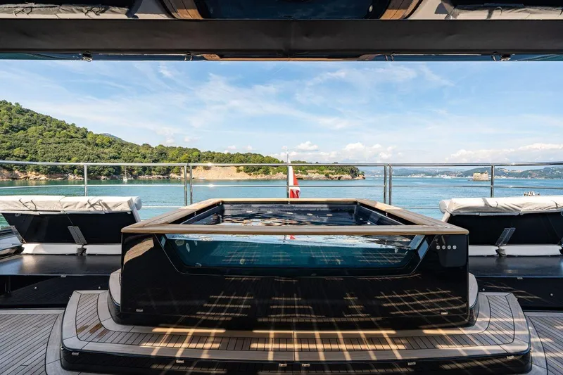 Petite Belle Yacht Photos Pics Luxurious Sunreef 100 Power yacht deck with jacuzzi, overlooking serene ocean and lush coastline, 2025 model.