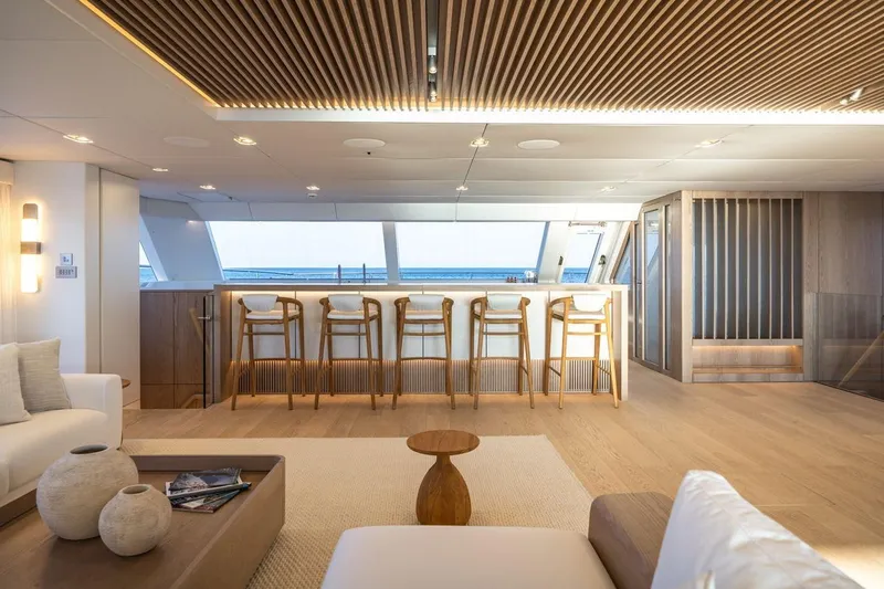 Petite Belle Yacht Photos Pics Luxurious interior of 2025 Sunreef 100 Power yacht with modern bar and seating area.