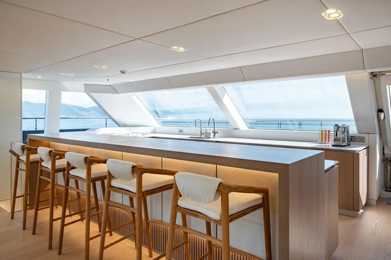 Petite Belle Yacht Photos Pics Luxurious interior of 2025 Sunreef 100 Power yacht with modern bar and ocean view.