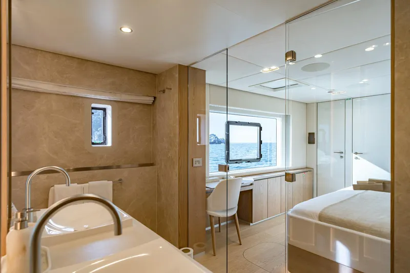 Petite Belle Yacht Photos Pics Luxurious interior of 2025 Sunreef 100 Power yacht, featuring elegant bedroom and bathroom with ocean view.