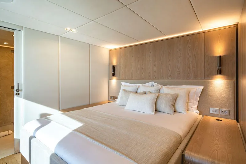 Petite Belle Yacht Photos Pics Luxurious bedroom interior on 2025 Sunreef 100 Power yacht, featuring elegant wood paneling and ambient lighting.