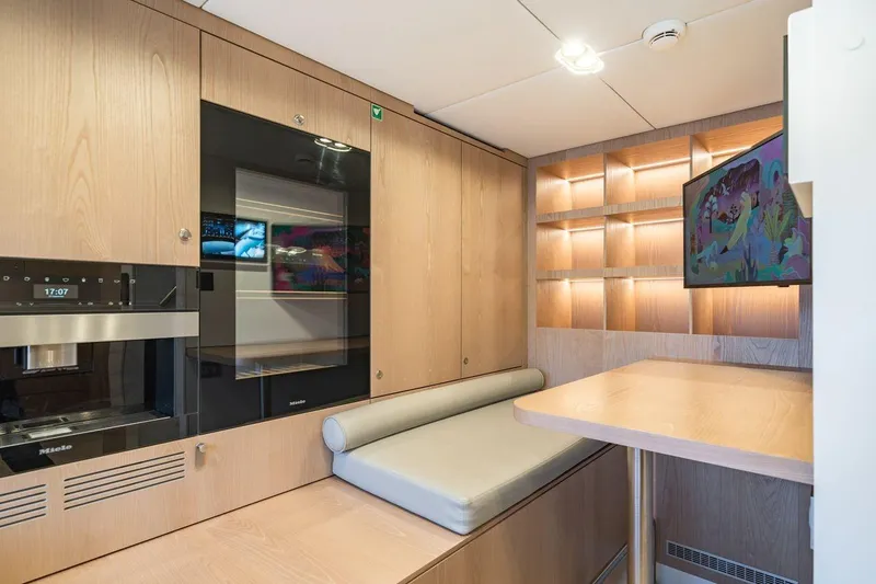 Petite Belle Yacht Photos Pics Modern interior of 2025 Sunreef 100 Power yacht with sleek wood finishes and built-in appliances.