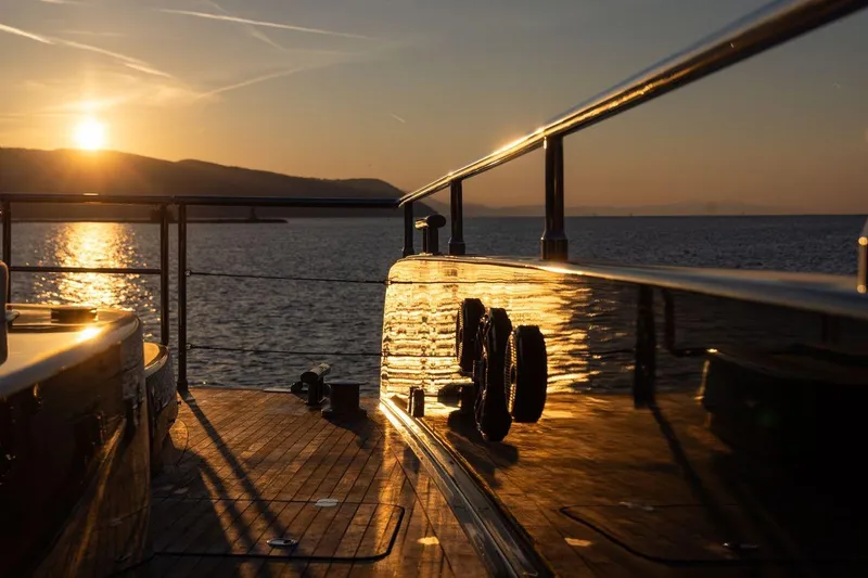 Petite Belle Yacht Photos Pics Sunset view from 2025 Sunreef 100 Power yacht deck, reflecting golden hues on the water.