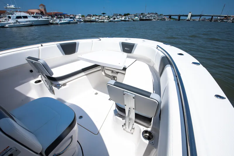  Yacht Photos Pics 2023 Robalo R270 Center Console boat interior with seating and table, docked in a marina.