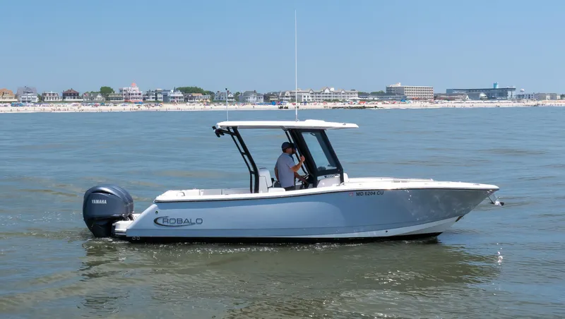  Yacht Photos Pics 2023 Robalo R270 Center Console boat cruising near a coastal town.