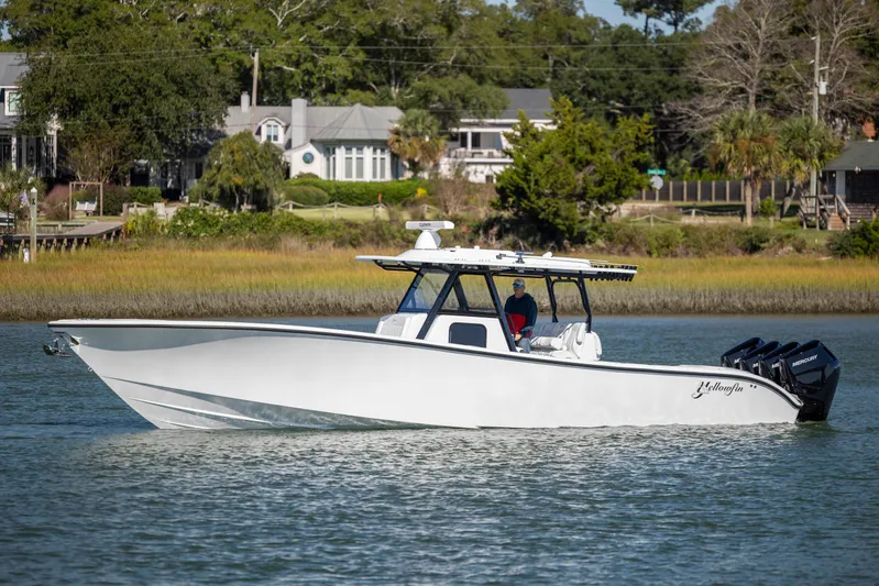  Yacht Photos Pics 2026 Yellowfin 39 Offshore boat cruising on a calm river near a residential area.