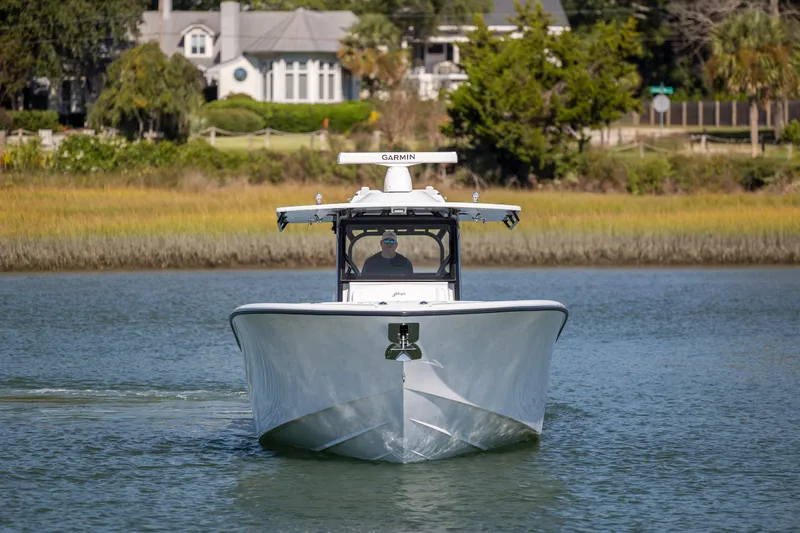  Yacht Photos Pics 2026 Yellowfin 39 Offshore boat cruising on a calm waterway, surrounded by lush greenery.